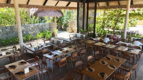 a restaurant with wooden tables and chairs at ANGKLA Beach Club & Boutique Resort in El Nido