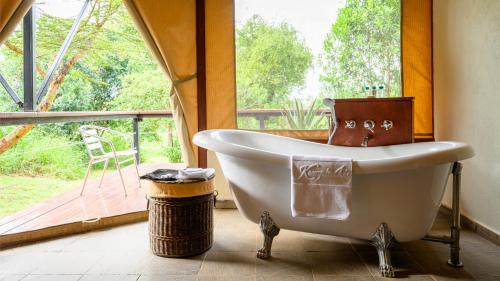 a bath tub in a bathroom with a large window at Olare Mara Kempinski in Talek