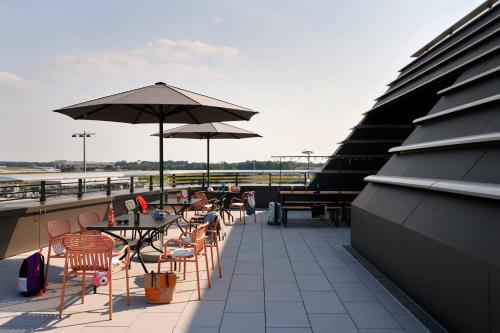 a patio with tables and chairs and umbrellas on a roof at Moxy Cologne Bonn Airport in Cologne