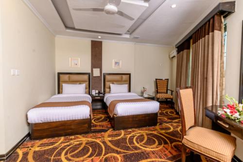 a hotel room with two beds and a desk at Hotel One Abbottabad in Abbottābād