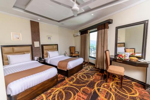 a hotel room with two beds and a desk at Hotel One Abbottabad in Abbottābād