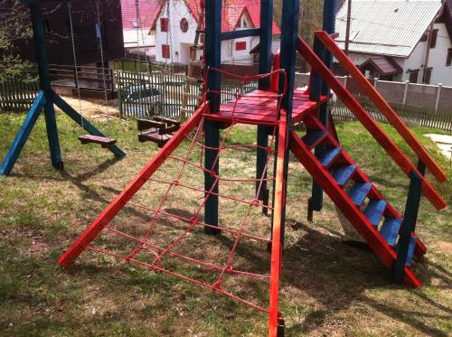 a playground with a red slide in the grass at Franzdorf Alpin in Văliug