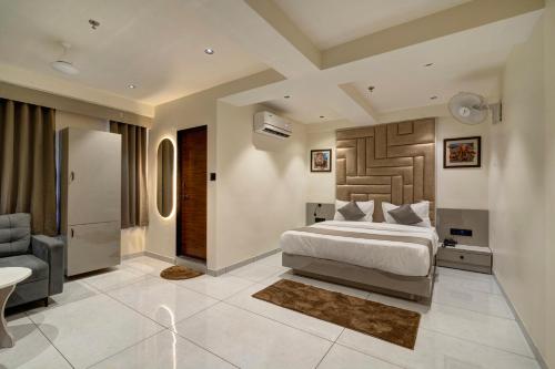 a bedroom with a king sized bed and a chair at Hotel Shrimad Villa Gandhinagar in Gandhinagar
