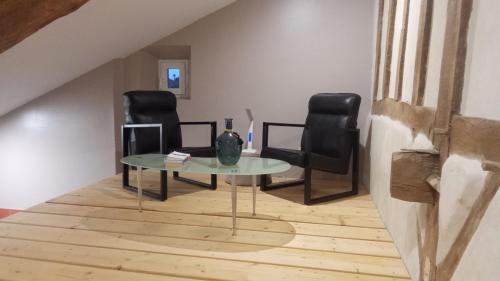 a room with two black chairs and a glass table at La Coquille in Pouillon