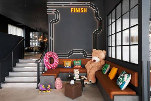 a teddy bear sitting on a couch in a room at Moxy Milton Keynes in Milton Keynes