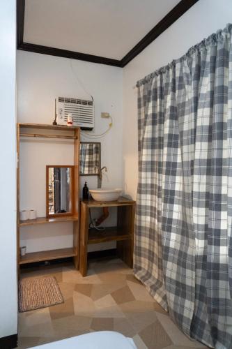 a bathroom with a shower curtain and a table at Shelves Siargao in General Luna