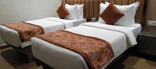 two beds in a hotel room with white sheets and brown pillows at Grand Continent - Bangalore International Airport in Devanahalli-Bangalore