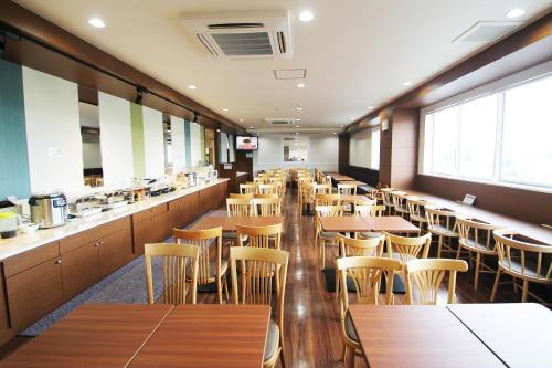 a restaurant with wooden tables and chairs and a bar at Vessel Hotel Kumamoto Airport in Ozu