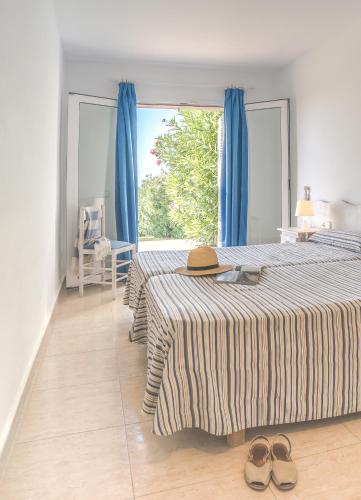 a bedroom with two beds and a window with blue curtains at Apartamentos Mar Blau in Son Bou