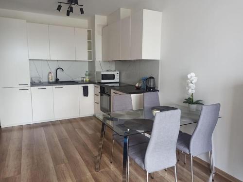 eine Küche mit Glastisch und weißen Schränken in der Unterkunft Apartament 24 Gdynia Zachód in Wiczlino