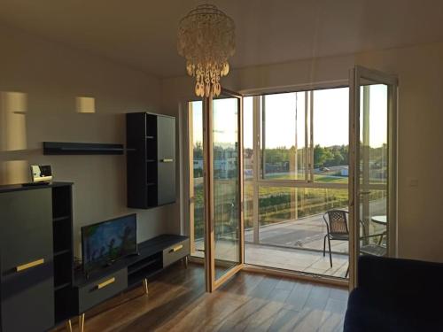 ein Wohnzimmer mit Fernseher und großer Glastür in der Unterkunft Apartament 24 Gdynia Zachód in Wiczlino