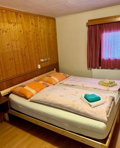 a bedroom with a bed with orange pillows and a window at SKILL Mountain Lodge - Ski und Bike Hostel im Sommer mit JOKER CARD in Saalbach Hinterglemm
