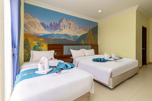 two beds in a room with a painting on the wall at Lisha Roungnakhone Hotel in Vang Vieng