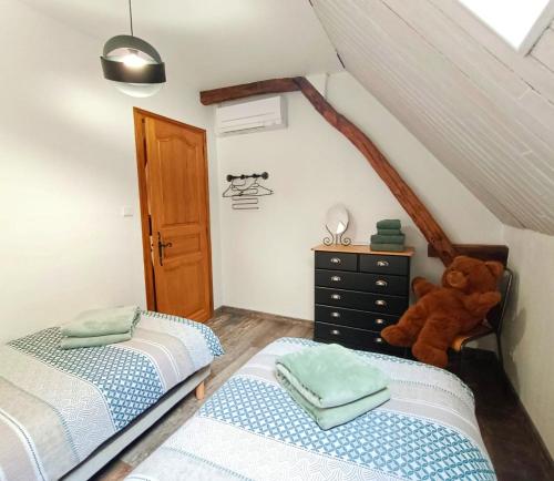 a attic bedroom with two beds and a teddy bear at Gîte de la Peyre et du Causse in Florimont-Gaumiers