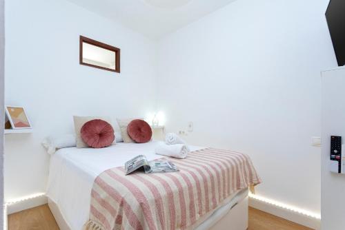 a white bedroom with a white bed with red pillows at Sunstay Center Flat I Arroyo De La Miel in Benalmádena