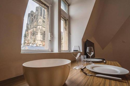 une table avec une plaque, deux verres et une fenêtre dans l'établissement Family avec vue sur la Cathédrale de Reims, à Reims