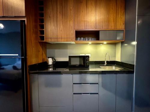 a kitchen with a sink and a microwave at Escape Condominiums Beachfront Suites - Mae Phim in Rayong