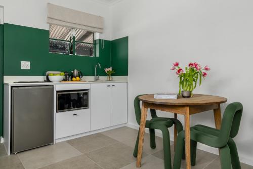 a kitchen with green walls and a wooden table and chairs at Neighbourgood Franschhoek in Franschhoek