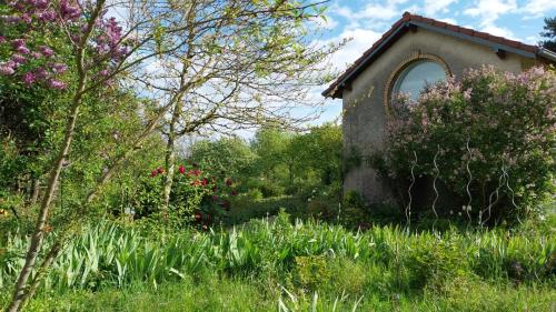 a garden with a building and some flowers at Gîte La Cour Cachée in Saulx-en-Woëvre