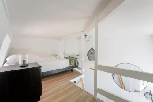 une chambre blanche avec un lit et un miroir dans l'établissement Studio avec mezzanine pour 2 personnes, à Lille
