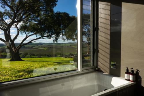 a bath tub in front of a window with a view at Barossa Pavilions & Glasshouse in Lyndoch