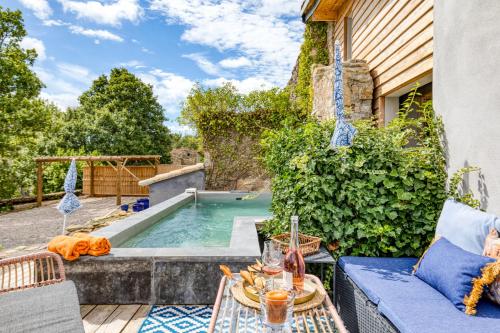 une terrasse avec une piscine, une table et des chaises dans l'établissement Le Mas de Coeur, à Bédarieux