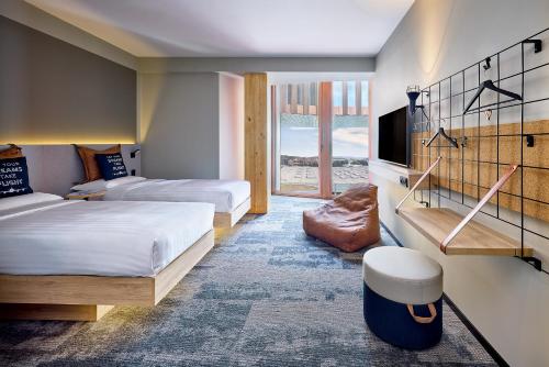 a hotel room with two beds and a television at Moxy Luxembourg Airport in Luxembourg