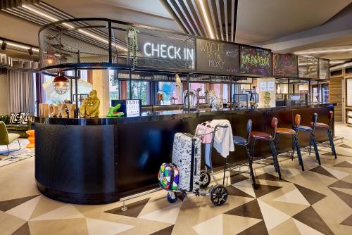 a restaurant with a bar with a cart in front of it at Moxy Luxembourg Airport in Luxembourg