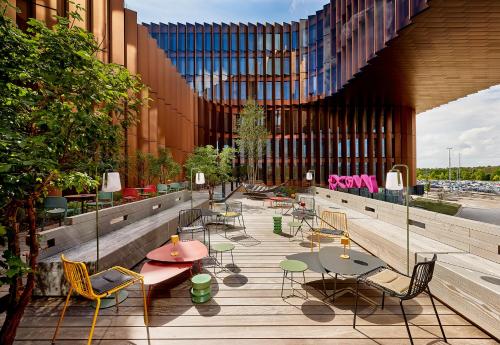 a patio with tables and chairs and a building at Moxy Luxembourg Airport in Luxembourg