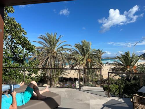a person laying on a couch looking at the beach at Hotel Capo San Vito by Geocharme in San Vito lo Capo