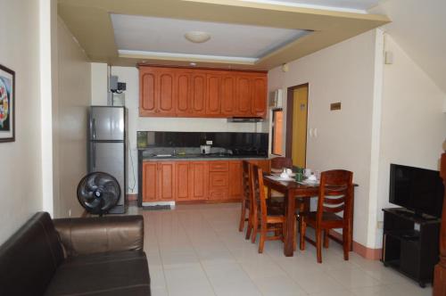 a kitchen with a table and chairs and a refrigerator at Manora Apartment in Talisay