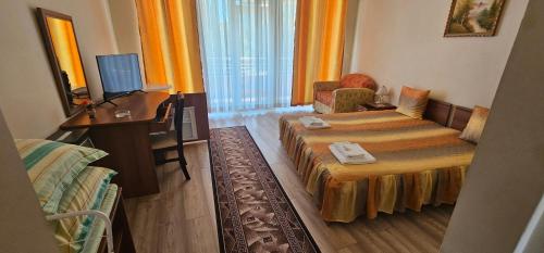 a hotel room with a bed and a desk and a television at Hotel Venecia in Primorsko