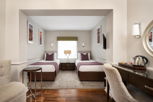 a hotel room with two beds and a table at Millbrook Lodge in Ballynahinch