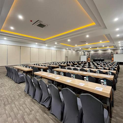 una gran sala con filas de mesas y sillas en Front One Hotel Airport Solo, en Solo