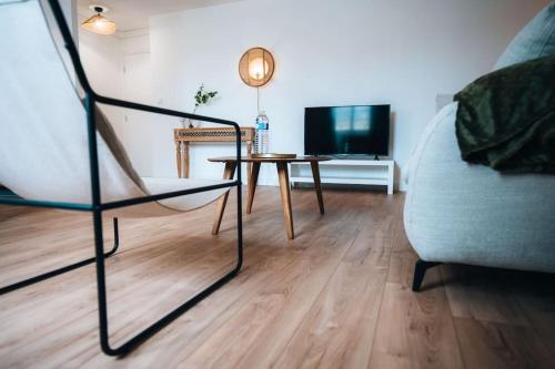 a living room with a table and a chair and a television at Le Berry Soft - Spacieux & Chaleureux - Proche Gare in Châteauroux