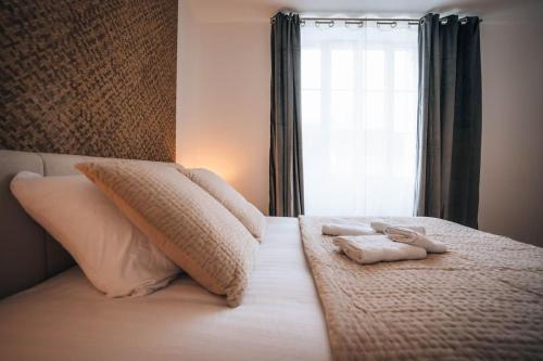a bed with two towels on it with a window at Le Berry Soft - Spacieux & Chaleureux - Proche Gare in Châteauroux