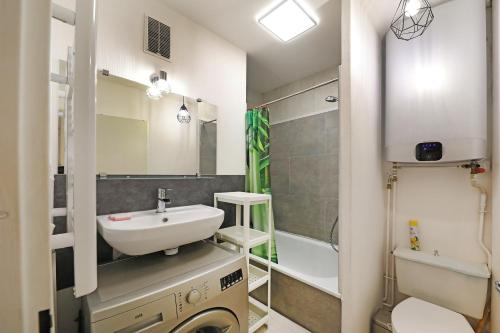 une salle de bain avec un lavabo et une machine à laver dans l'établissement Le Carbet des Oursons - Appt à Bresse vue montagne, à La Bresse