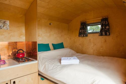 a small bedroom with a bed in a tiny house at Barbara Shepherds Hut in Kent