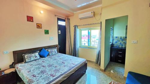 a bedroom with a bed with blue pillows and a window at Anandam Home Stay in Rishīkesh