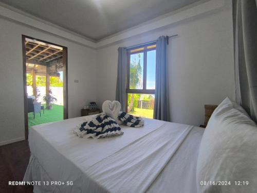 a white bed with two pillows on it with a window at U Story Resort in Siquijor