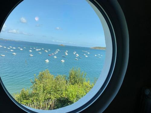 a round window looking out at the water with boats at Ty Lazo: Sérénité en bord de mer, havre de paix. in Plouézec