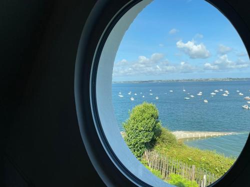 a round window looking out at a large body of water at Ty Lazo: Sérénité en bord de mer, havre de paix. in Plouézec