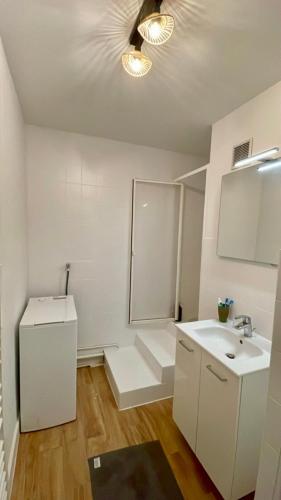 une salle de bain blanche avec un lavabo et un miroir dans l'établissement Appartement rénové 76m2 proche plage, à La Rudelière
