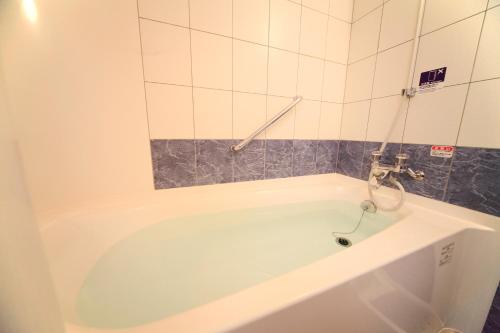 a bath tub with a faucet in a bathroom at Vessel Hotel Kumamoto Airport in Ozu