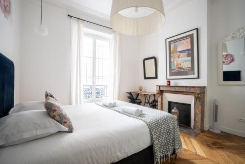 une chambre blanche avec un lit et une cheminée dans l'établissement GuestReady - A classic touch of Parisian glamour, à Paris