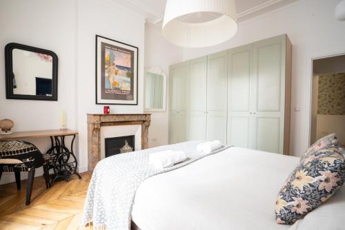 - une chambre avec un lit blanc et une cheminée dans l'établissement GuestReady - A classic touch of Parisian glamour, à Paris