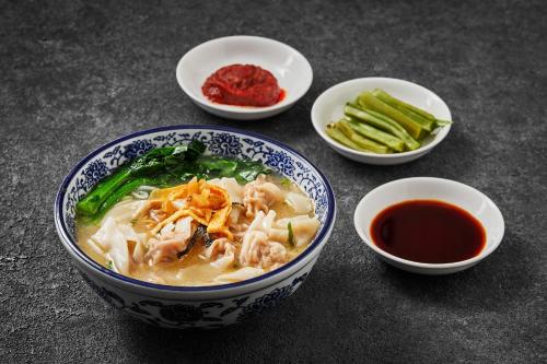 a bowl of chicken noodle soup and bowls of sauce at Crowne Plaza Suzhou by IHG in Suzhou