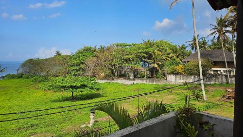 a view of a grassy hill with a house and the ocean at Pondok Pisces Bungalows Balian Beach in Selemadeg