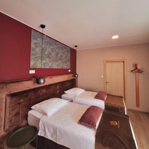 two beds in a hotel room with red walls at Boutique Hotel St Georgije in Banja Luka
