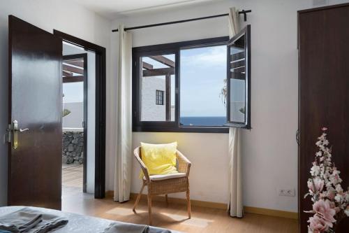 a room with a chair and a window with a yellow pillow at Playa Marina Ocean View Eco Bungalow in Arrieta